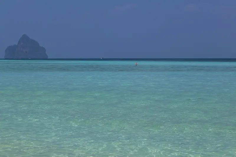 Turquoise shallows off Ko Kradan, with a rocky island in the distance