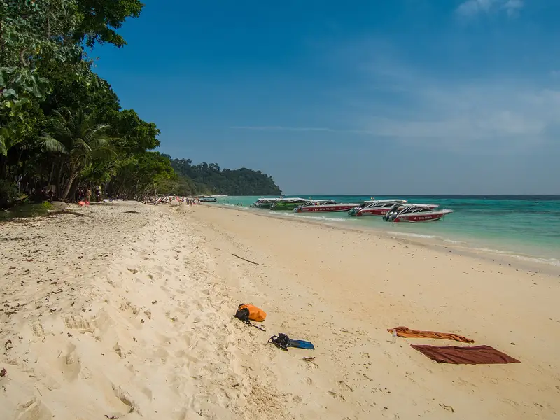 Speedboats lined up along a long white-sand beach on Koh Rok
